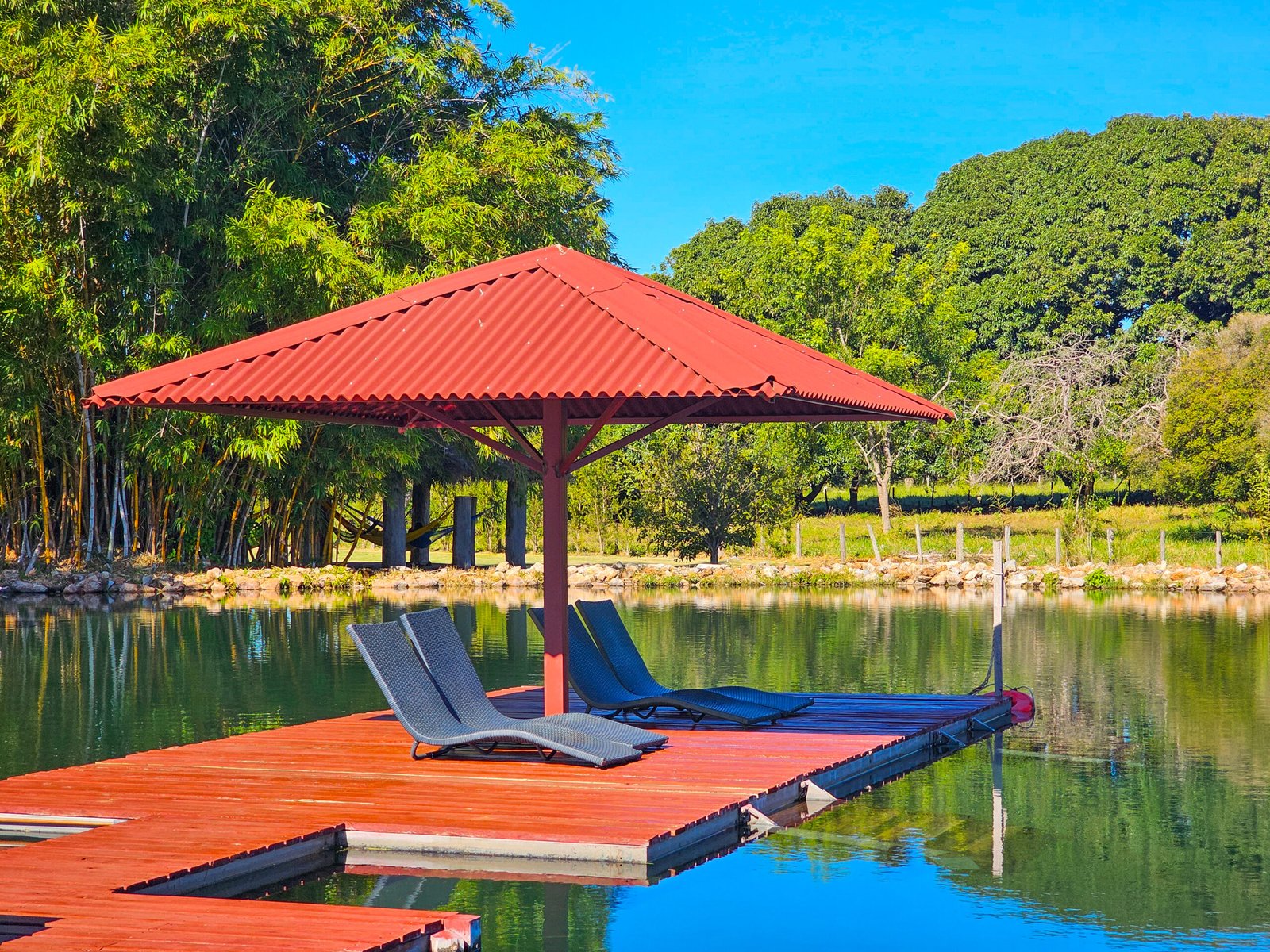 cadeiras de descanso com cobertura em meio a um lago de fazenda