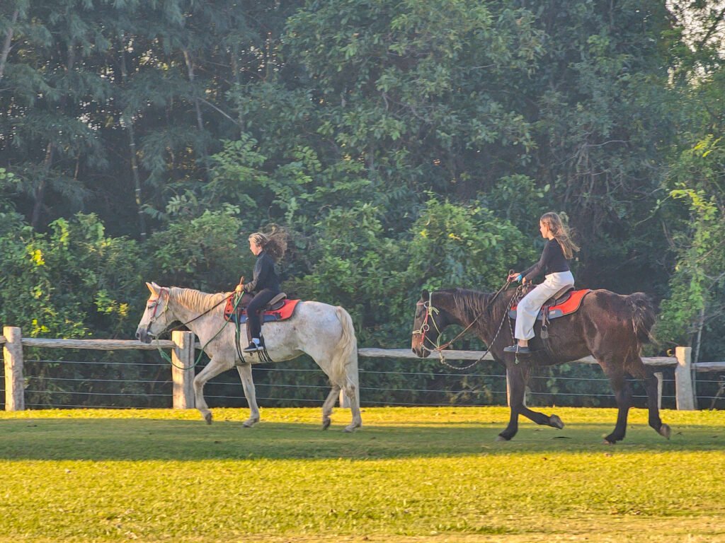 Duas pessoas cavalgando na propriedade.