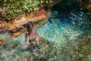 Mulher em água cristalina com peixes.