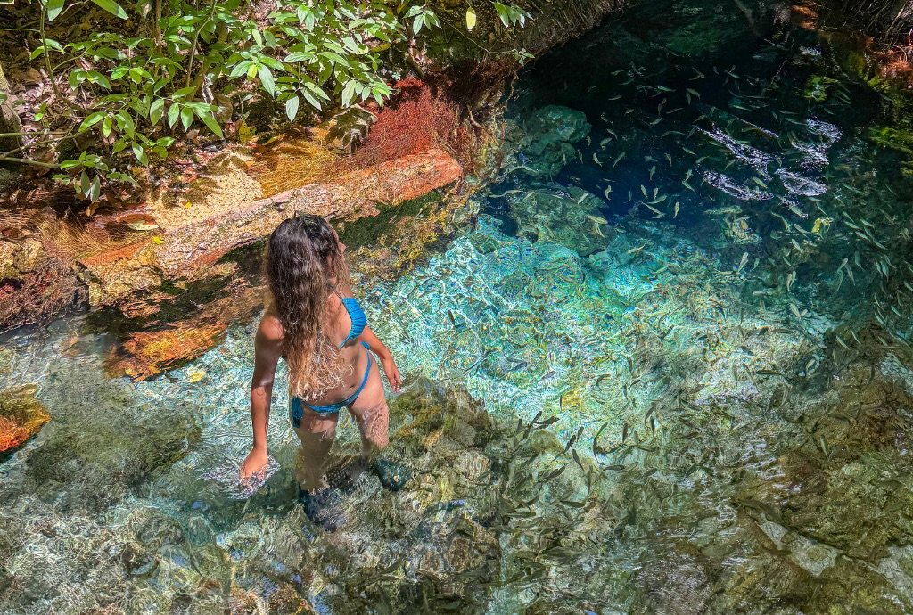 Mulher em água cristalina com peixes.